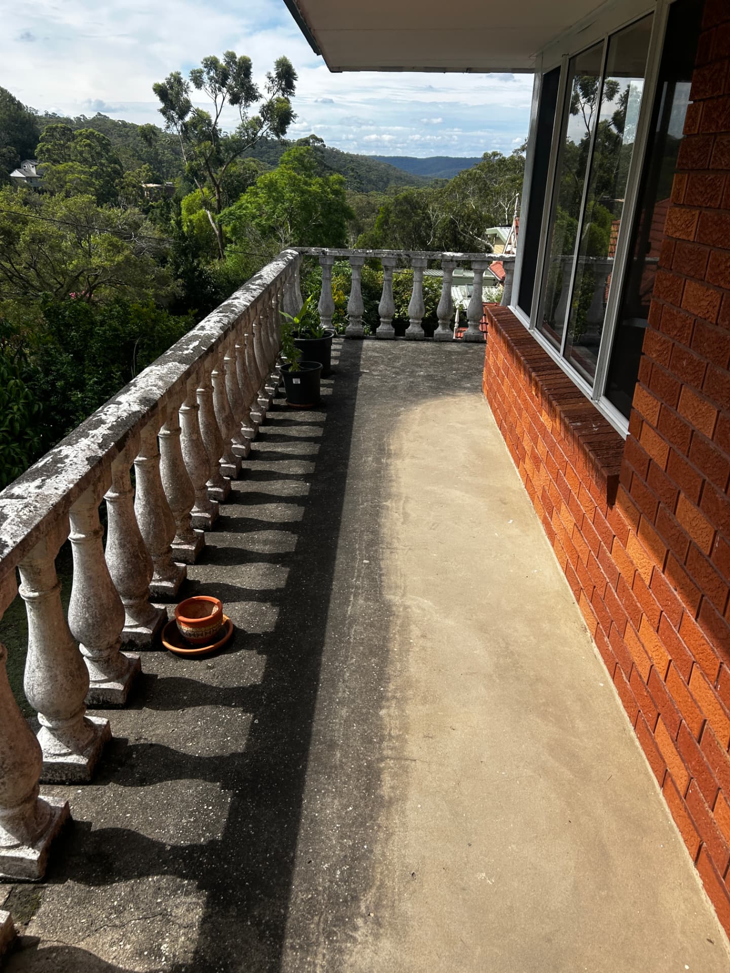 Concrete balcony half cleaned, showing the dirt line between washed and unwashed sections